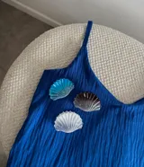 Broche con forma de concha marina en color azul, blanco y marrón.