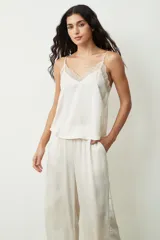 Blusa color crudo con lunares dorados, breteles finos y escote en V con detalle de encaje.