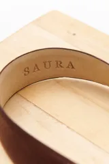 Cinturón marrón de cuero con hebilla metálica plateada con diseño floral.