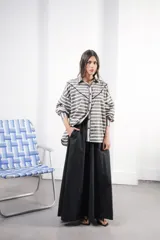 Camisa color crudo a rayas, de corte oversized con hombros caídos y silueta amplia. Presenta un recorte delantero con vivo contrastante, botones al frente y logo bordado al frente.