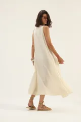 Vestido largo color crudo, de lino, con escote en V, corte acampanado y bolsillos laterales.