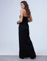 Vestido de fiesta corto strapless, color negro, confeccionado en crepe. Presenta escote recto con aplique de moño en satén y tajo en la parte delantera.