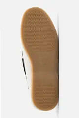 Zapato náutico de cuero blanco con detalles en negro y suela marrón.