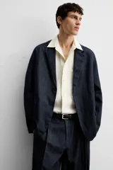 Blazer azul oscuro de denim, corte relaxed fit, con cuello de solapas de muesca, manga larga con puños abotonados, bolsillos de solapa en la cadera, abertura en el centro de la espalda y cierre frontal con botones. Sin forro interior.