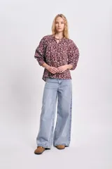 Blusa de manga larga color bordó con estampado floral en blanco, cuello redondo con lazo ajustable y corte holgado.