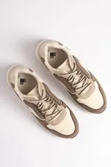 Zapatillas deportivas acordonadas combinadas en tonos beige, crema y marrón.