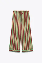 Pantalón de pijama de viscosa con estampado de rayas verticales en verde, rojo y amarillo. Tiene tiro medio, cintura elástica ajustable con cordones, bolsillos laterales y pierna ancha.