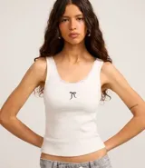 Musculosa de rib color blanco de la marca Blue Steel, con escote redondo ribeteado en encaje y detalle de moña negra bordada en el centro del pecho.