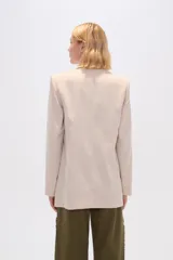 Blazer color beige de lino, con cuello solapa, corte holgado y bolsillos laterales.