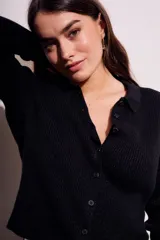 Cardigan negro de punto con cuello polo, manga larga y cierre frontal con botones.