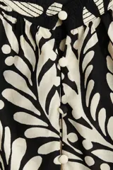 Blusa oversized de algodón y viscosa con estampado de hojas y lunares en blanco y negro. Tiene cuello mao, abertura frontal con botones forrados, mangas globo largas con puños abotonados y bajo redondeado.