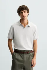 Polo de piqué color crudo, corte regular fit, cuello solapa con cierre de botonadura y mangas cortas.
