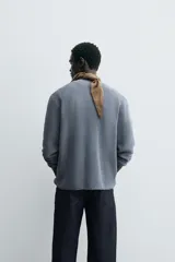 Sweater azul de punto con textura, corte holgado, cuello redondo y mangas largas con puños acanalados.
