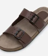 Sandalias slide marrones de cuero sintético con dos tiras ajustables con hebillas metálicas negras y plantilla anatómica.