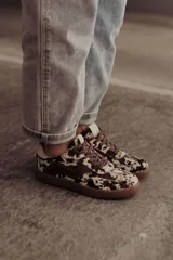 Zapatillas bajas de cuero color marrón con suela de goma color caramelo y cordones marrones.