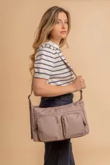 Bandolera de tafeta impermeable, liviana, con dos compartimientos principales, dos bolsillos con cierre y correa regulable con hebilla.