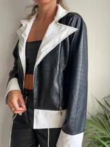 Campera de cuero sintético negro y blanco con diseño contemporáneo y cierre frontal.