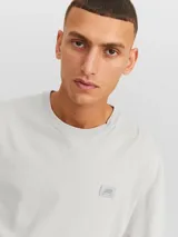 Camiseta gris claro de manga corta y cuello redondo con calce amplio.
