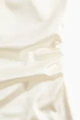 Vestido corto de breteles finos color blanco, con escote recto y frunces laterales que generan un efecto drapeado.