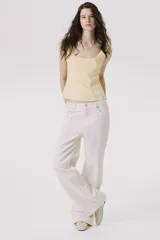 Musculosa color crema con breteles anchos, escote cuadrado, pinzas en el busto y cintura entallada con costuras visibles.