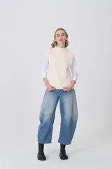 Chaleco de punto color crema, sin mangas, con cuello alto y textura acanalada vertical.