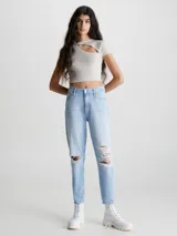 Jeans celeste claro de corte mom, con roturas en las rodillas, tiro alto, cinco bolsillos y cierre con botón y cremallera.