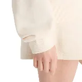 Buzo color crema de corte holgado, cuello redondo y logo bordado en el pecho.