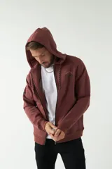 Campera de felpa color bordó con capucha y cordón ajustable, cierre frontal con cremallera, bolsillos laterales y logo estampado en el pecho.