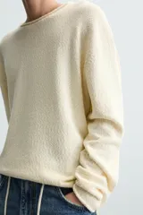 Jersey color crudo de algodón con textura, corte relaxed fit, cuello redondo y manga larga. Acabados en rib con detalle de vuelta.