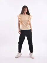 Remera blanca de cuello redondo con detalle de volados que nacen en los hombros y bajan por el frente.