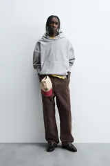 Sudadera gris con capucha ajustable, corte boxy fit, manga larga, bolsillo tipo canguro y estampado en la espalda.