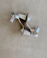 Sandalias plateadas con tira delantera, tobillera con hebilla y taco geométrico.