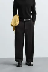 Pantalón negro de corte amplio, tipo balloon fit, con pinzas en la cintura, bolsillos laterales y traseros de ojal.