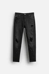 Pantalón de jean negro con corte skinny fit, cinco bolsillos, lavado con efecto roto y cierre frontal con cremallera y botón.