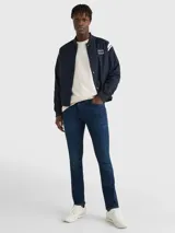 Jeans de denim azul oscuro con efecto desteñido en la parte delantera, corte ajustado, cierre de cremallera con botón y diseño de cinco bolsillos.