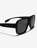 Lentes de sol unisex Hawkers modelo Parlay, con montura cuadrada negra y lentes grises.