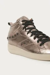 Zapatilla tipo botita de cuero color peltre con recortes y pespuntes a tono, remaches en forma de estrella con baño negro, cordones de algodón encerado negros, acceso lateral con cierre, cuero marcario en la lengüeta, suela de goma y forrería interior color camel.