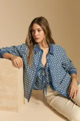 Camisa de manga larga, color azul, con cuello camisero y estampado geométrico en blanco. Presenta un diseño de doble capa: una camisa exterior abierta con botones y un top anudado debajo.