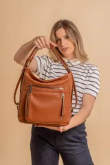 Cartera mochila color marrón de símil cuero suave con múltiples bolsillos con cierre, división al medio y correa ajustable de doble manija para llevar al hombro y como mochila.