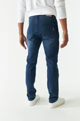 Jean azul oscuro de corte recto, con tiro medio, roturas en la pierna y logo bordado en el bolsillo trasero.