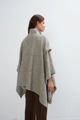 Capa beige con diseño de espiga, cuello alto, cierre frontal con botones ocultos y bolsillos plaqué. Aberturas laterales que se pueden cerrar para usar como poncho o ruana.