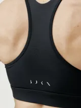 Top deportivo negro de alta sujeción, con corte atlético y pieza en curva para ajuste perfecto. Interior de tejido mesh para mayor ligereza y copas extraíbles.