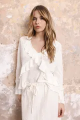 Blusa blanca de lino con escote en V y volados en el frente. De corte recto y mangas largas.