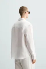 Camisa de manga larga color celeste claro, con cuello solapa y cierre frontal de botonadura. Presenta una textura sutil en el tejido.