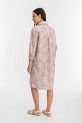 Vestido camisero midi de popelina de algodón con estampado floral en tonos rosa y rojo. Tiene cuello camisero, mangas largas con puños abotonados, cierre frontal con botones de nácar y tajos laterales.