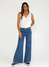 Pantalón de jean azul de corte palazzo con cintura alta y ruedo desflecado.