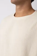 Remera color crudo de lino con textura entramada, calce cómodo y mangas cortas.