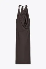 Vestido largo marrón oscuro con cuello halter y escote fluido. Tiene hombros descubiertos, detalle de pliegues laterales y forro interior a tono. Cierre lateral con cremallera oculta y en espalda con botones.
