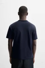Camiseta negra de algodón de corte regular, con cuello redondo con ribete doble y mangas cortas.