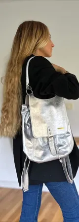 Mochila plateada con correa de hombro y tiras traseras ajustables.